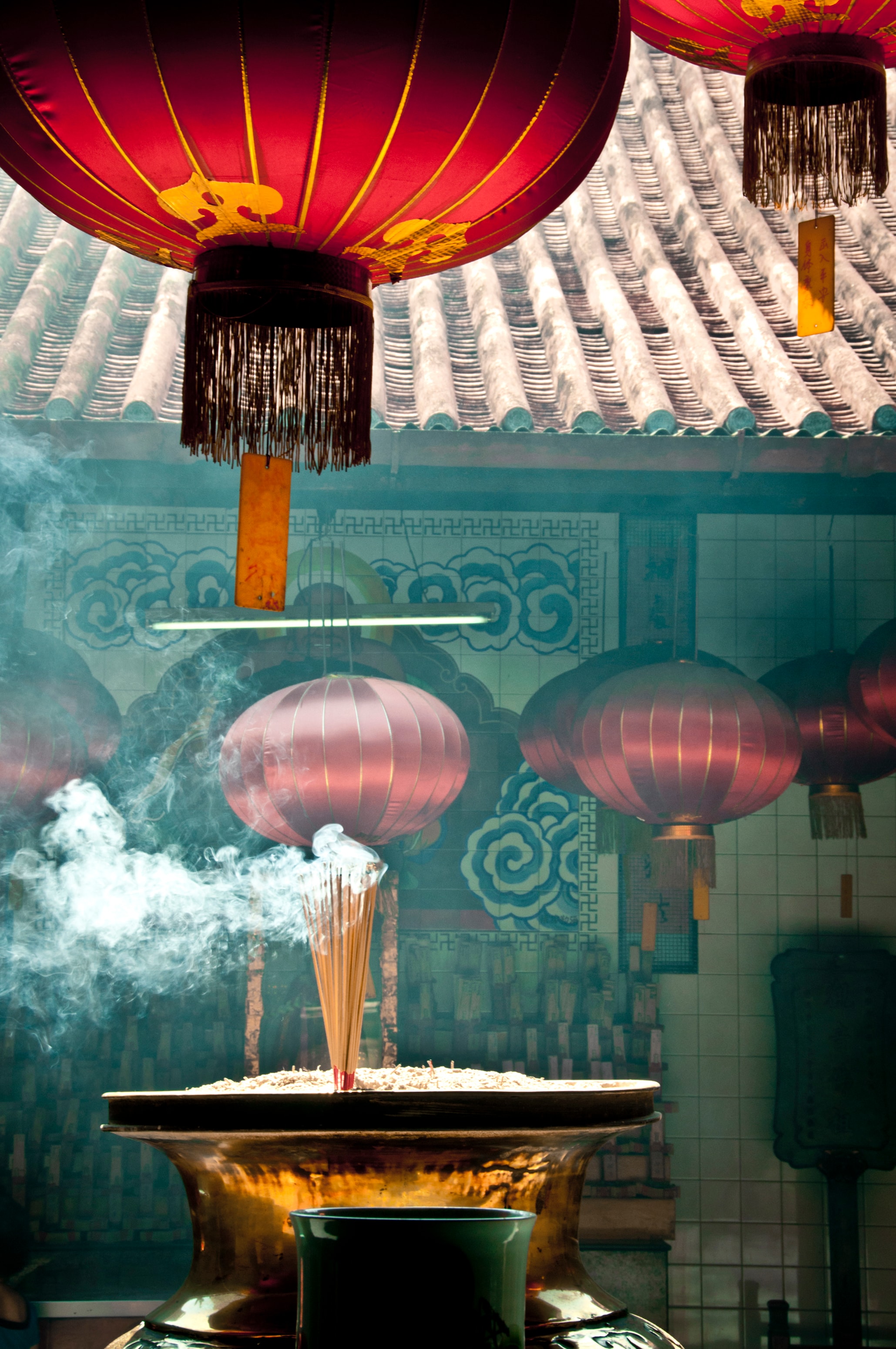 Red lanterns and incense smoke inside a temple